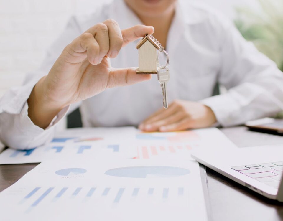 Tecnologia na escolha de lotes e imóveis para investir Real estate professional presenting a house model with keys, symbolizing property investment and ownership.