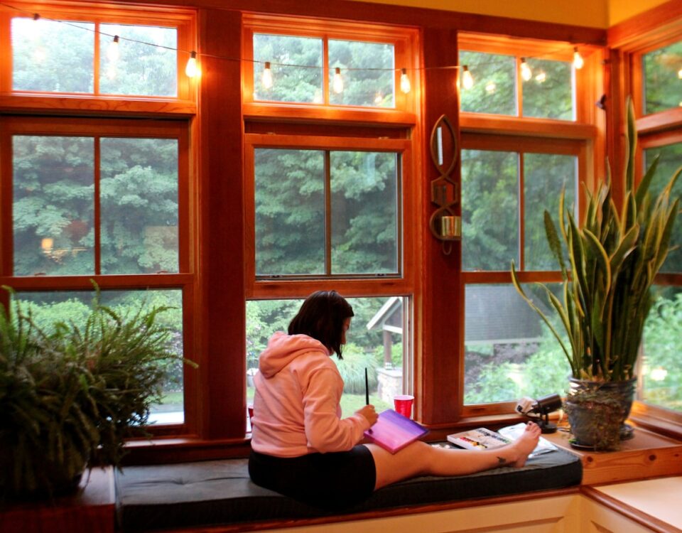 Aplicativos para explorar a arteterapia em casa woman in white long sleeve shirt sitting on brown wooden table