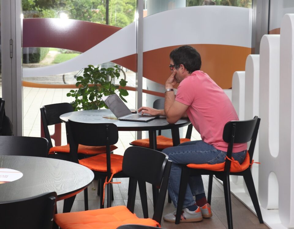 Ferramentas digitais para gestão de compras em bares A man sitting at a table using a laptop computer