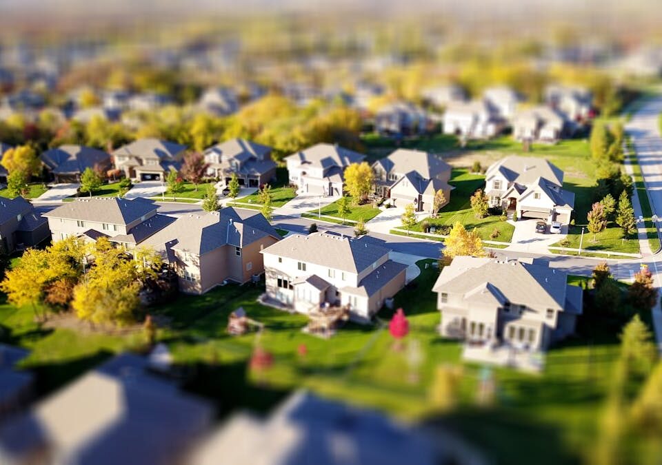 Ferramentas digitais para avaliar bairros antes de mudar Tilt-shift aerial photo of a suburban neighborhood with green lawns and roads.