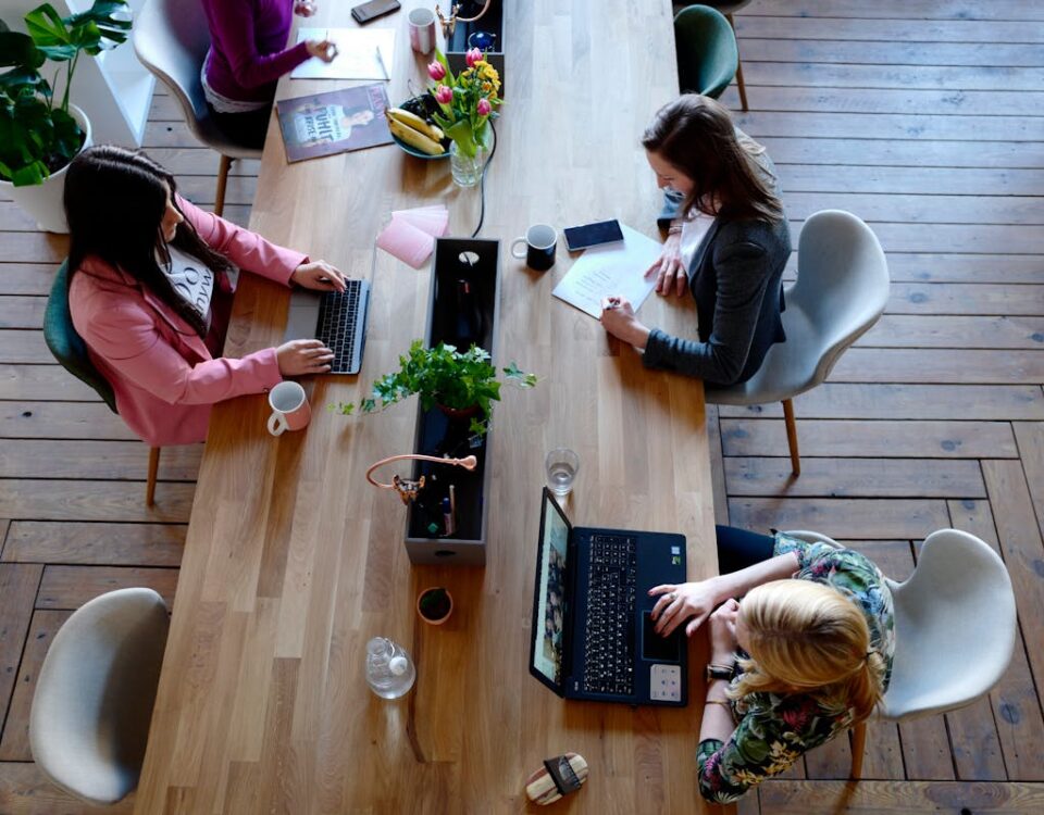 Dispositivos para melhorar a postura no escritório Overhead view of diverse women professionals working in a modern office setting, fostering collaboration and teamwork.