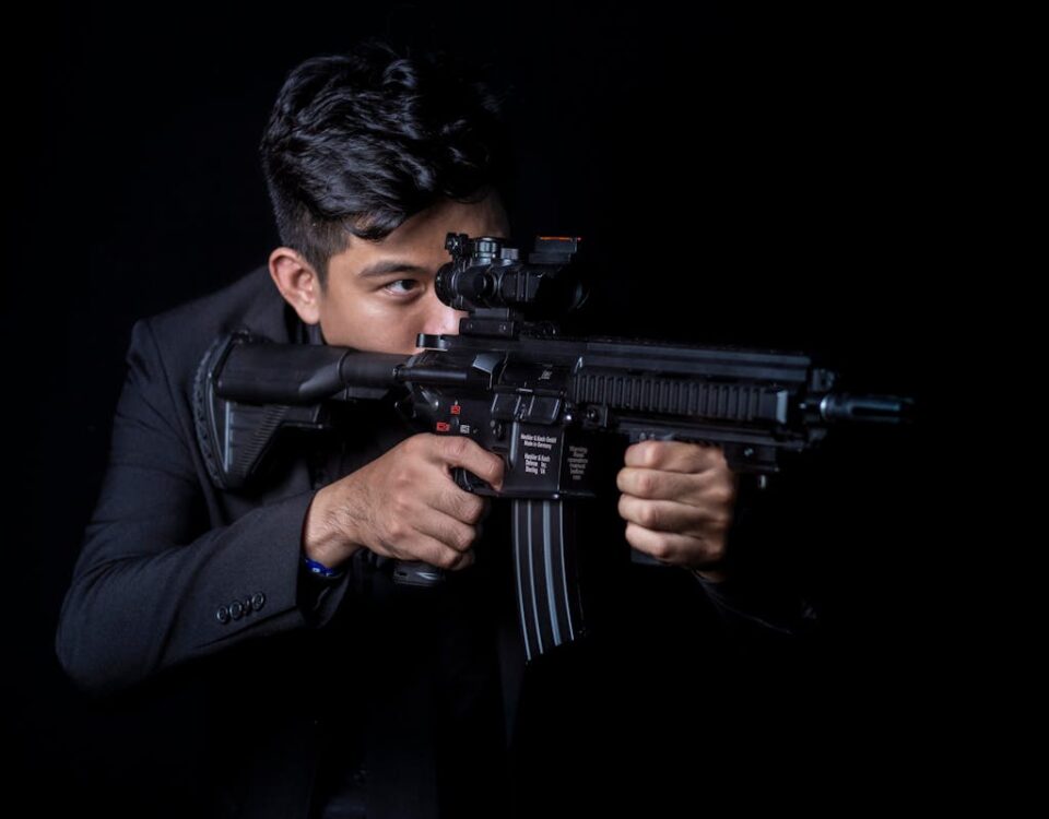 Como a tecnologia melhora a segurança de armas de fogo Portrait of a man aiming a rifle with a focused expression against a black background.