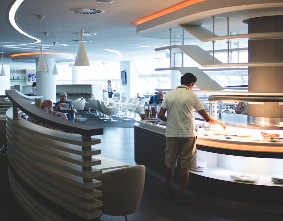 Como funcionam os cartões que oferecem acesso às salas VIP? Stylish airport lounge with buffet and seating, featuring sleek interior design and contemporary furniture.