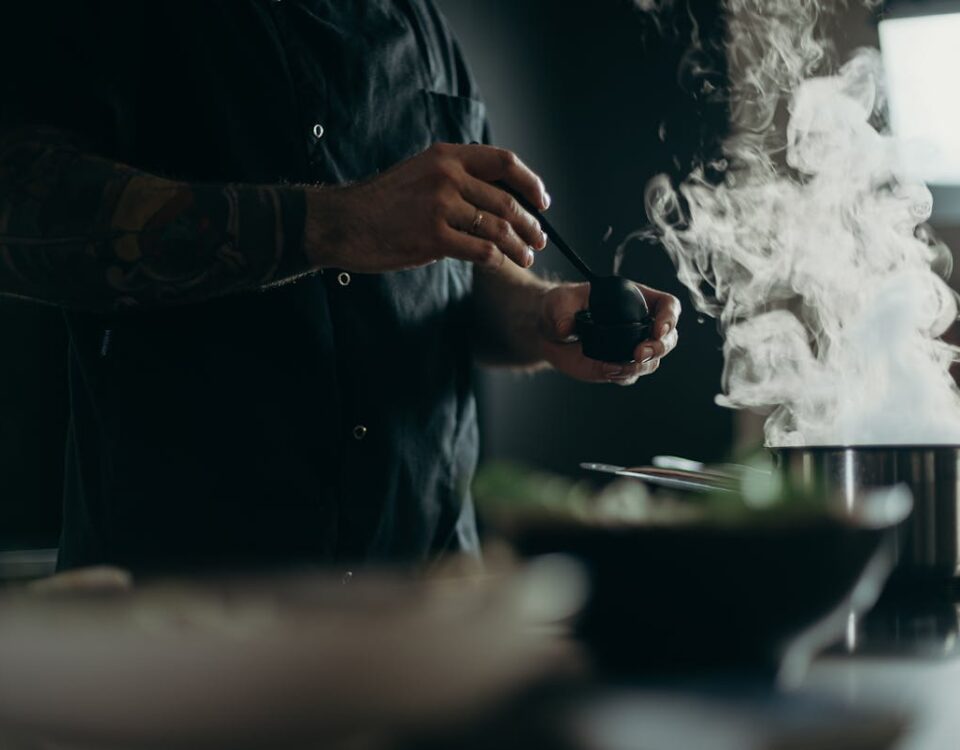 Tecnologia que transforma o preparo de receitas tradicionais A chef carefully prepares a steamy dish in a professional kitchen setting.