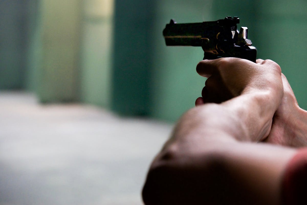 Close-up shot of hands aiming a pistol in an indoor shooting range, emphasizing focus and tension.