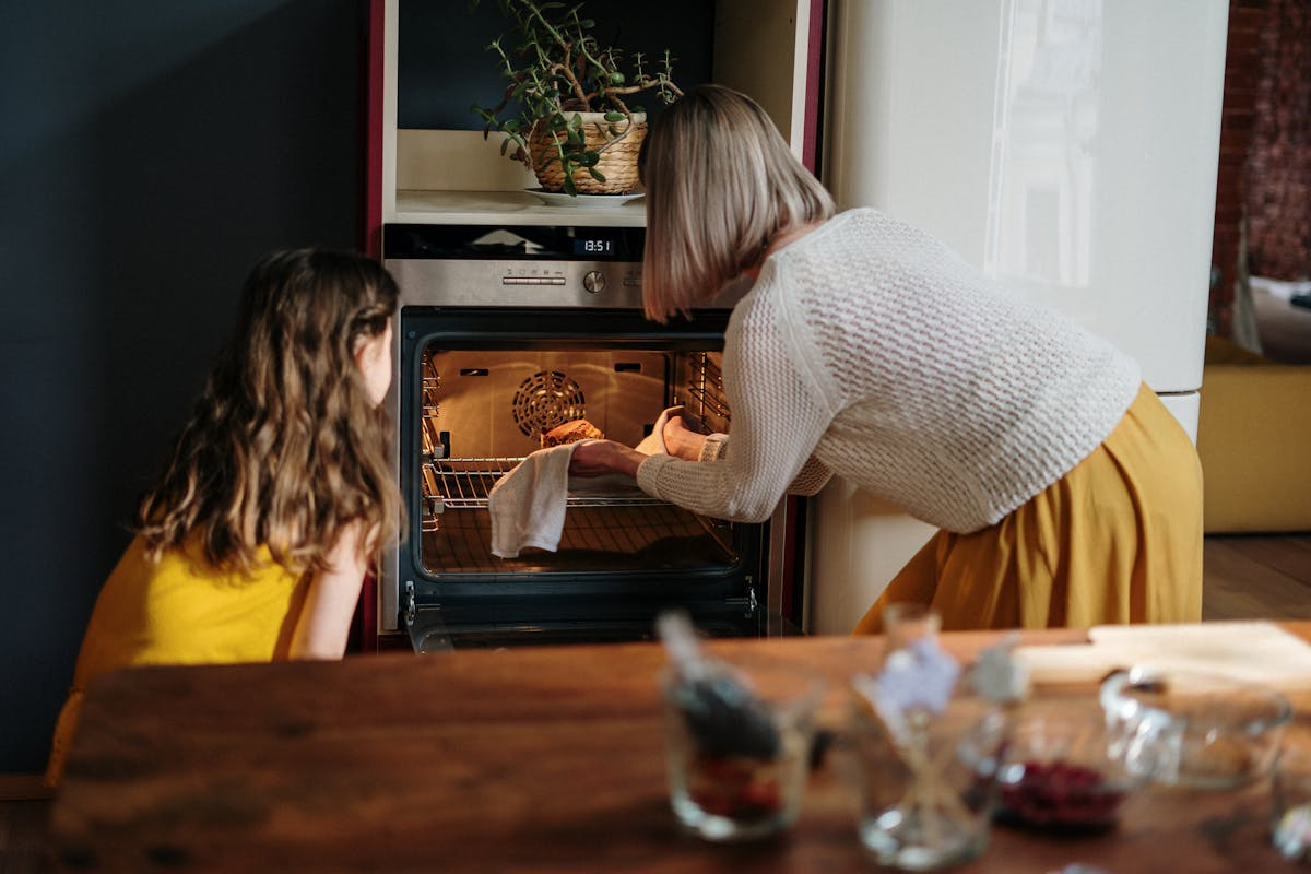Tecnologia que transforma o preparo de receitas tradicionais A mother and daughter baking a cake in a cozy kitchen setting, enhancing family time.