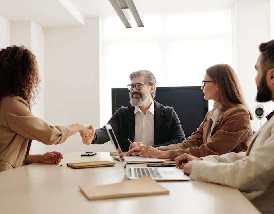 Como a tecnologia está transformando o mercado de seguros Colleagues in an office celebrating a successful negotiation with a handshake.