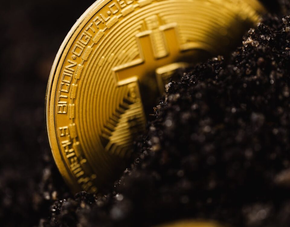 Como funciona a mineração de criptomoedas? A close-up shot of a Bitcoin partially buried in soil, symbolizing digital currency growth.