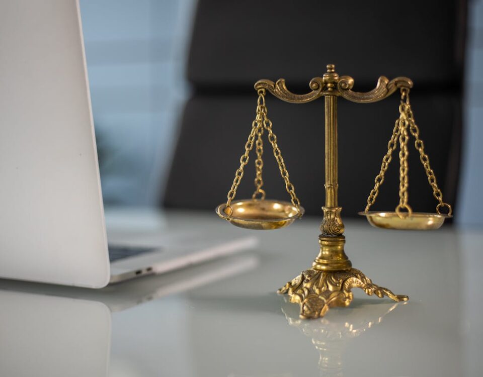 Tecnologia em tribunais: monitoramento digital em audiências Golden justice scales on a desk beside a laptop, symbolizing law and balance.