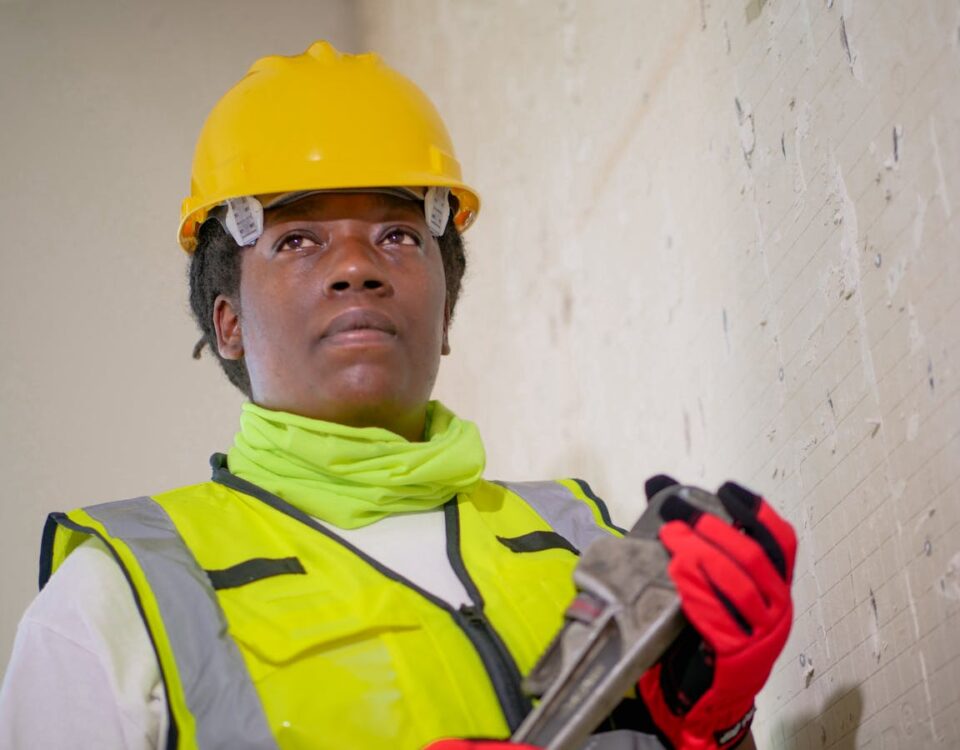 Tecnologia para detectar vazamentos de água em segundos Portrait of a female construction worker in safety gear holding a wrench indoors.