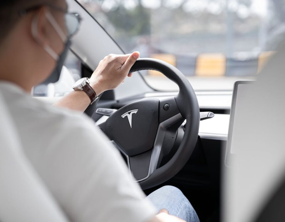 Como funcionam os carros com direção semiautônoma Close-up photo of a person driving a Tesla, showcasing modern vehicle interior design.