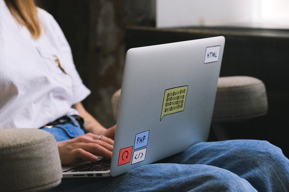 Inteligência artificial pode indicar o advogado certo? Person typing on a laptop with coding stickers, symbolizing remote work and freelancing.