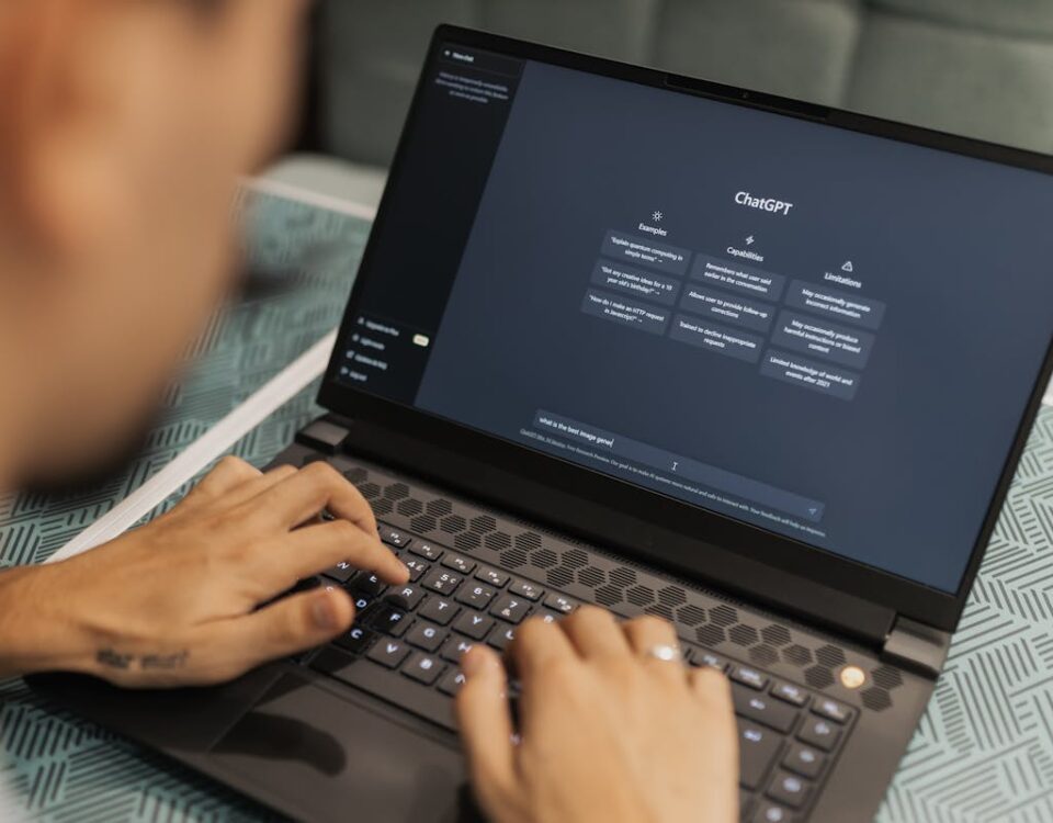 Close-up of a person typing on a laptop displaying the ChatGPT interface, emphasizing modern technology use.