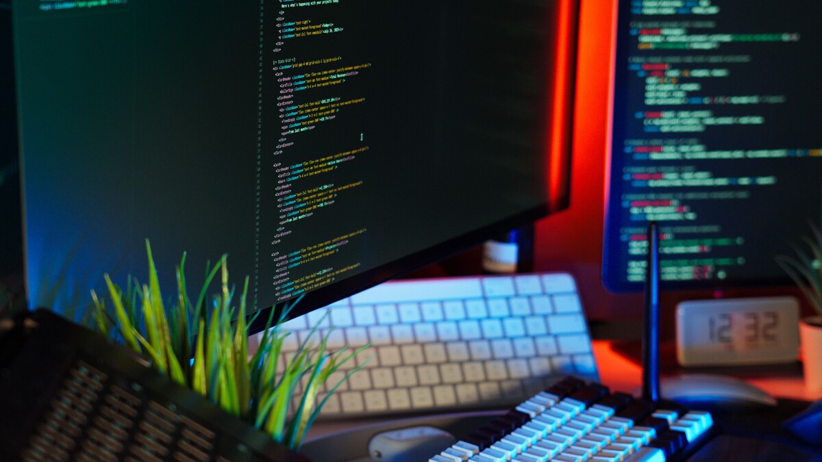 Mesa de trabalho com monitores exibindo código
