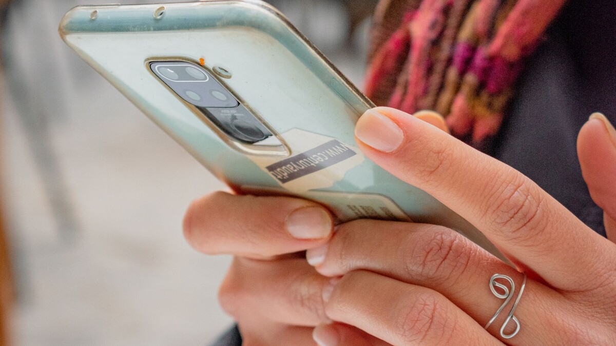 Mão segurando smartphone em ambiente externo