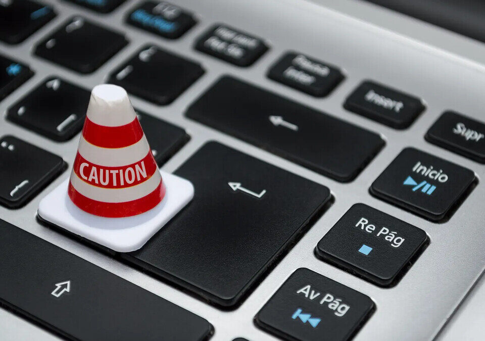 Cone de sinalização em miniatura sobre teclado de computador