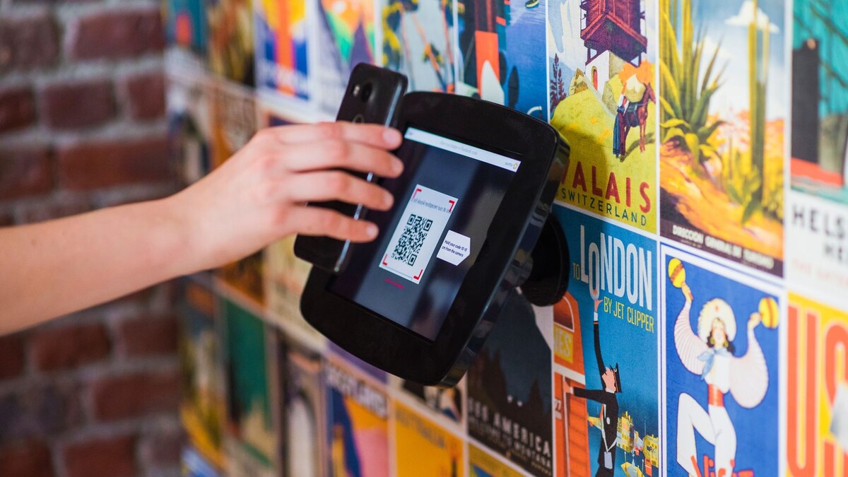 Mão segurando celular para escanear um QR Code em um balcão
