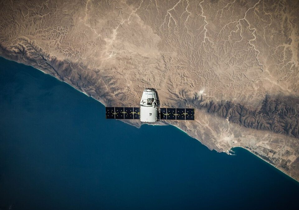 Satélite com painéis solares em órbita sobre o litoral visto do espaço
