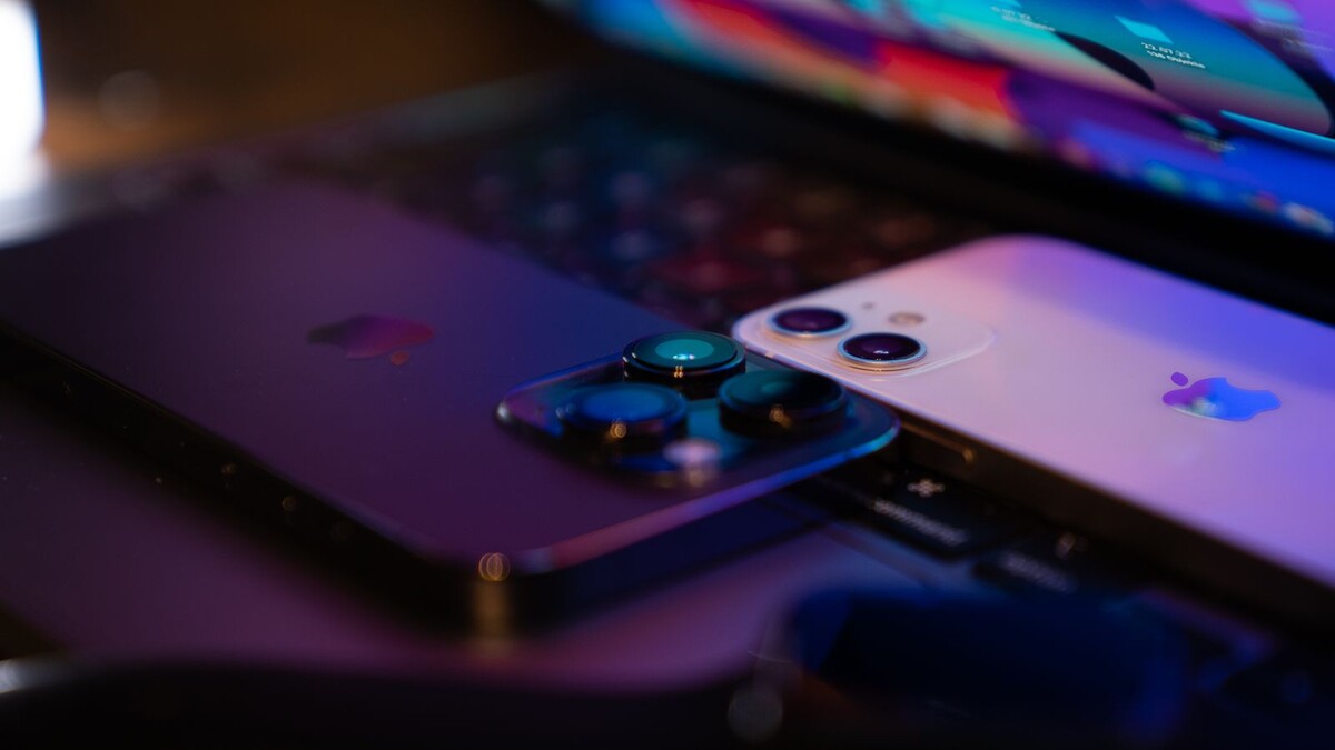 iOS 27.2 traz nova Siri em português: quais iPhones recebem Dois smartphones apoiados sobre um notebook