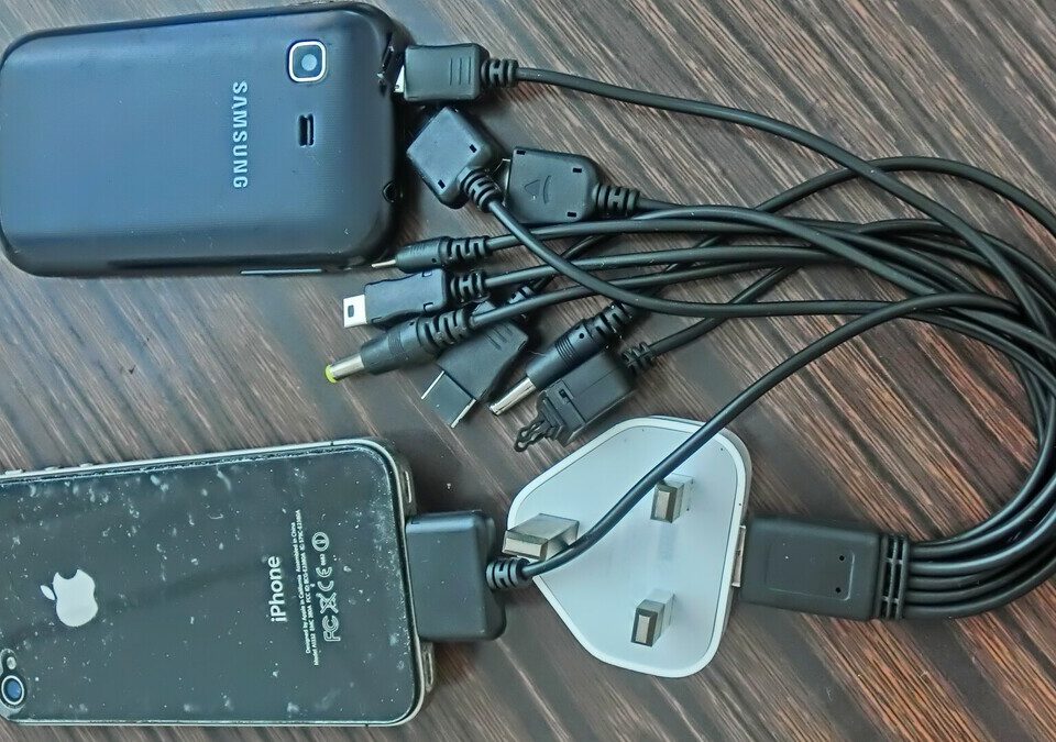 Celulares conectados a vários cabos de carregamento sobre uma mesa de madeira