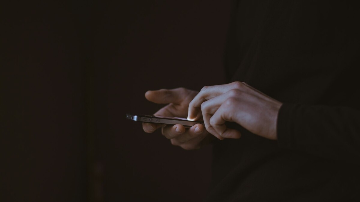 Silhueta de pessoa segurando celular contra a luz
