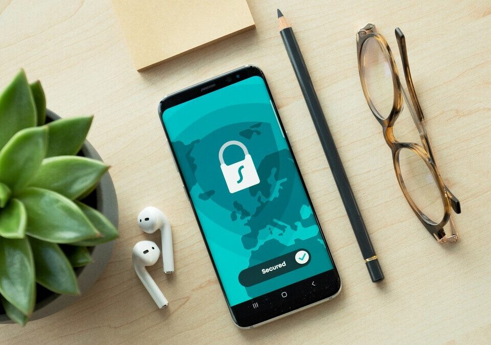 Smartphone com ícone de cadeado na tela sobre mesa de madeira ao lado de uma planta