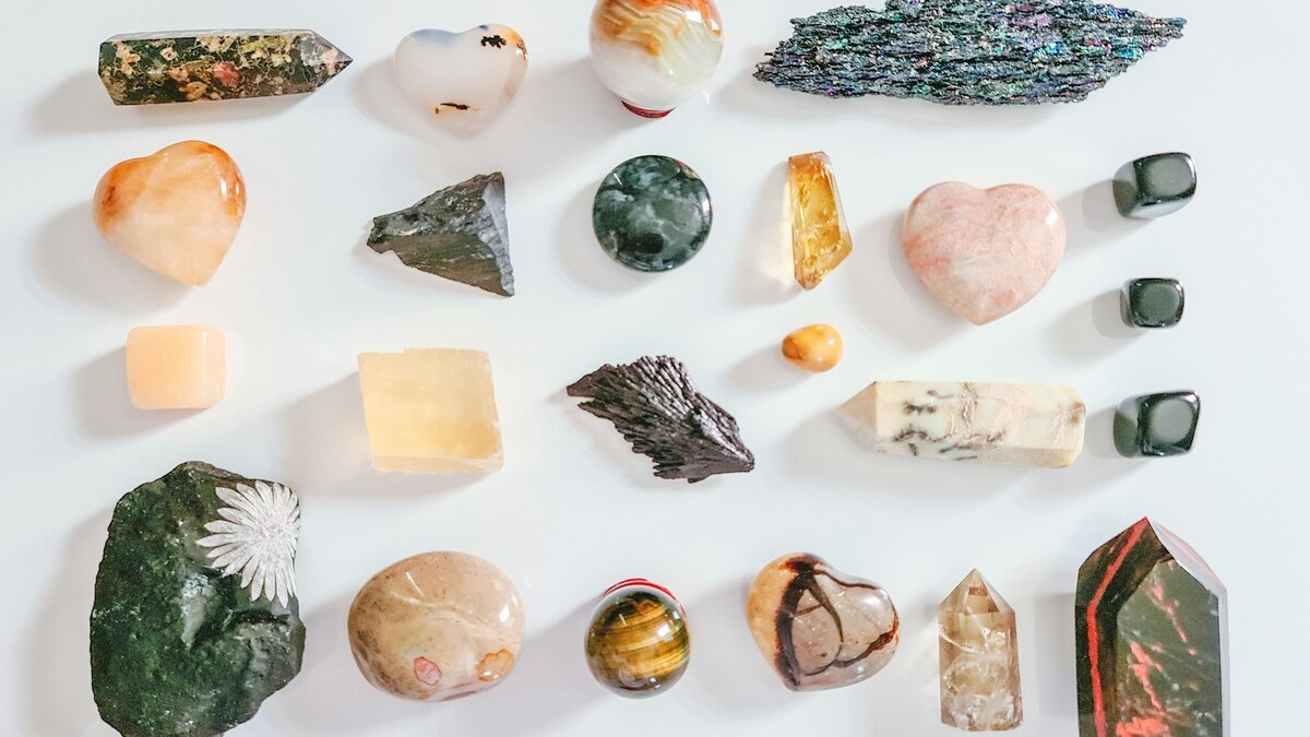 Meia aliança com pedra natural: como escolher a pedra certa Gemas lapidadas de várias cores sobre superfície branca