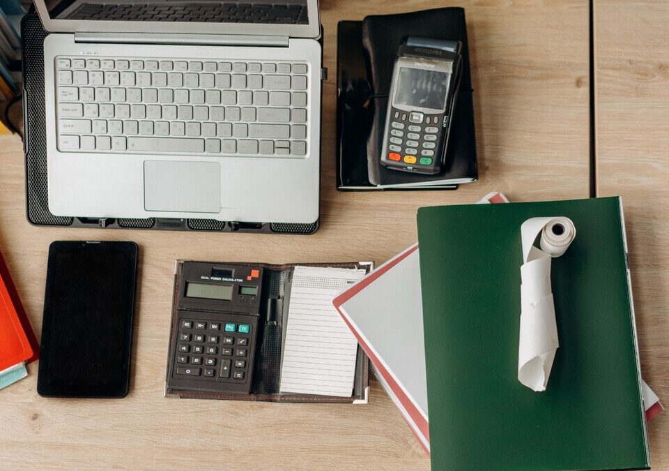 O que são dados próprios e como usá-los no marketing digital? Mesa de trabalho com notebook, celular, calculadora e materiais de escritório.