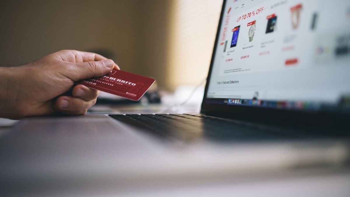 Pré-venda do iPhone Duo começou: preços, entrega e o que avaliar Pessoa segurando cartão de crédito diante de um notebook para compra online