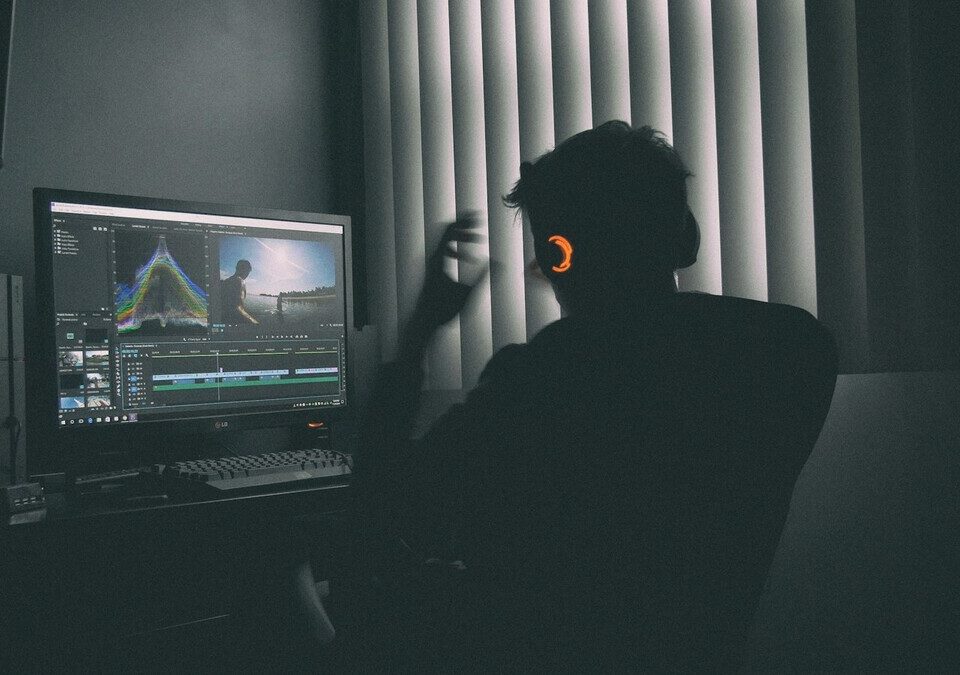 Pessoa editando vídeo em um computador em ambiente escuro