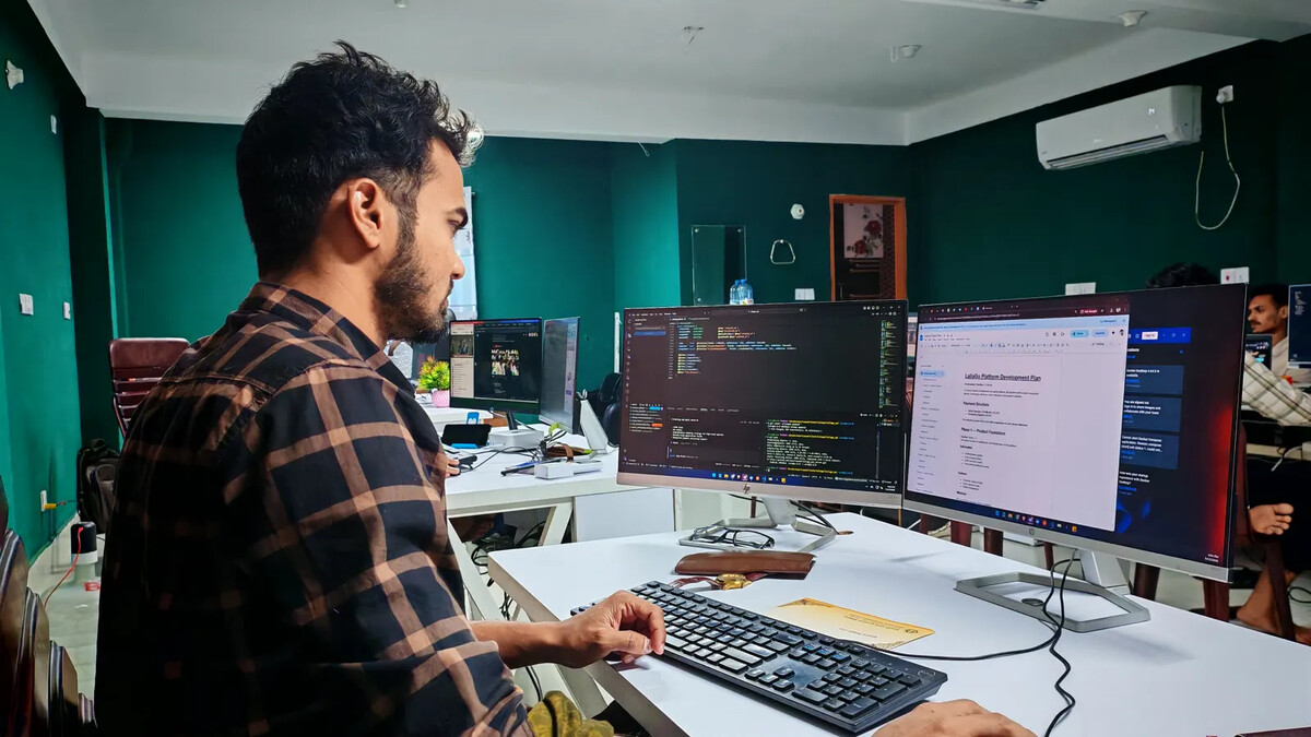 Sistema legado: quando modernizar e quando trocar de vez Desenvolvedor observando código em dois monitores